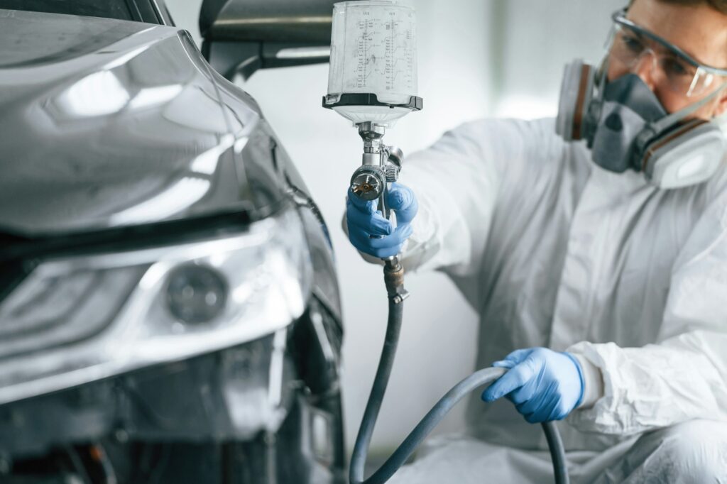 Man is painting a car by using spray guy