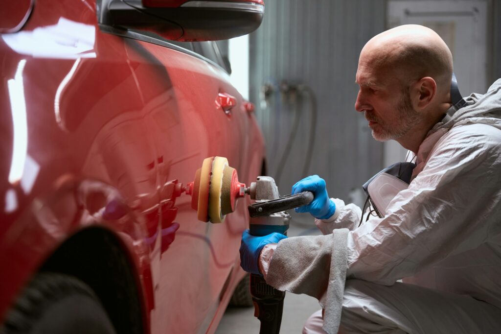 Man polishes body of red car after straightening and painting